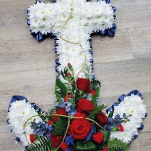 Anchor-shaped funeral flower arrangement with white chrysanthemums, red roses, and blue accents with gold rope.